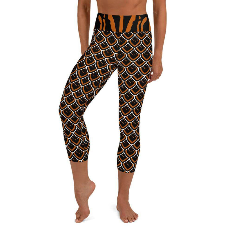 A person wearing black, orange and white scalloped pattern capri yoga leggings inspired by the black and gold sea slug.