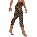 Right side view of black, gold sea slug capri leggings shows detail of the black wide waistband with vertical orange lines.