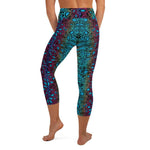 Back side view of a woman wearing workout capri yoga leggings with a crocea clam patterned on each side of leg.