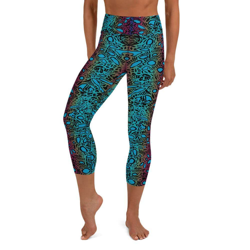 A person wearing capri yoga leggings, crocea clam pattern, black, turquoise, magenta, gold, small black circles, ovals, lines.