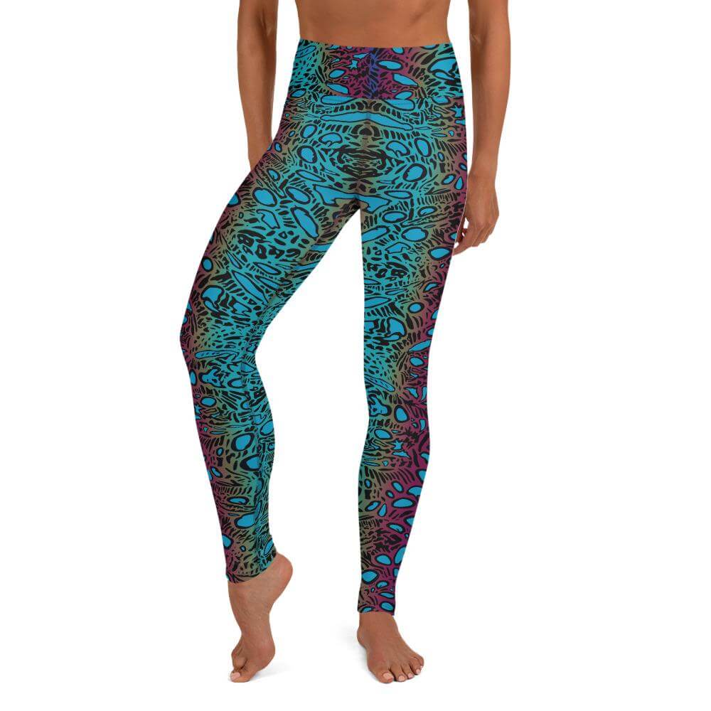 A woman wearing turquoise yoga leggings with crocea clam pattern black, magenta, gold and small black circles, ovals, lines.