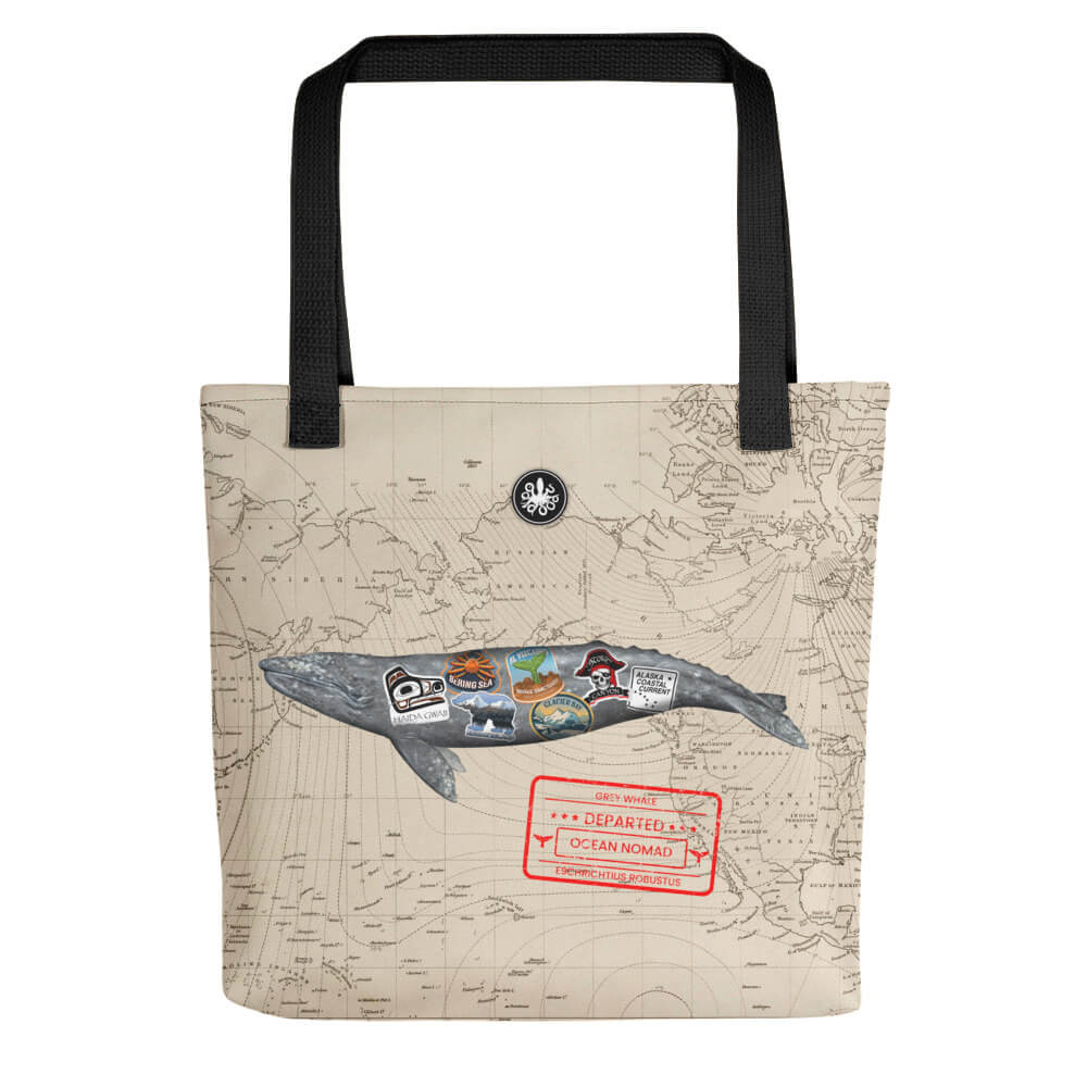 Tote bag with gray whale ocean nomad swimming, red travel stamp on lower right side, and thalassas logo at top.