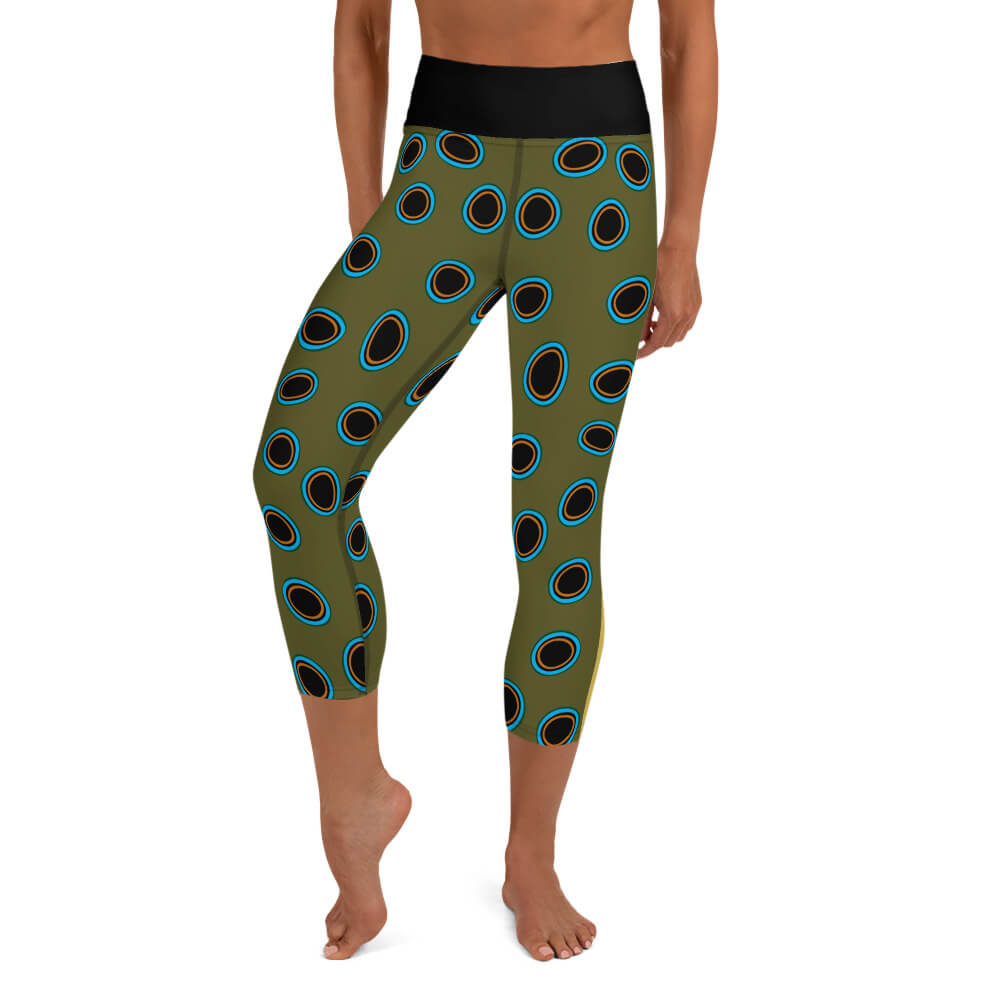 A person wearing olive green capri yoga leggings, spotted mandarin inspired pattern, black ovals outlined in turquoise, gold.