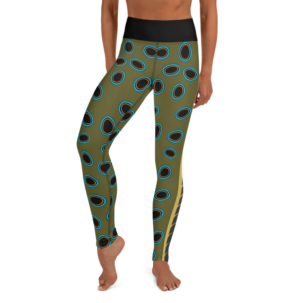 A person wearing olive green yoga leggings in a spotted mandarin inspired pattern of black ovals outlined in turquoise, gold.
