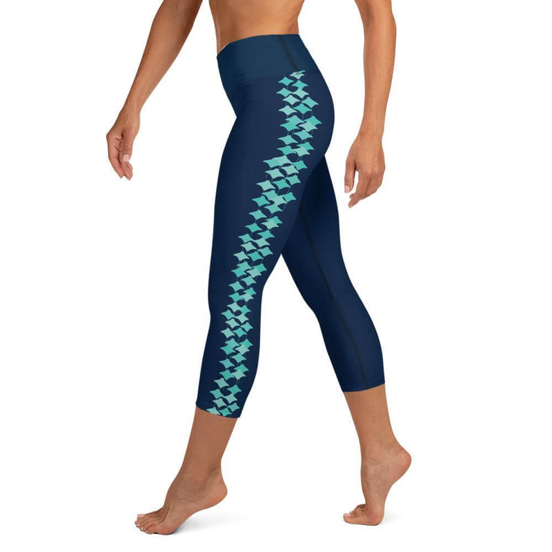 Left side view of person wearing navy blue capri leggings, turquoise stingray pattern on the side of each leg.