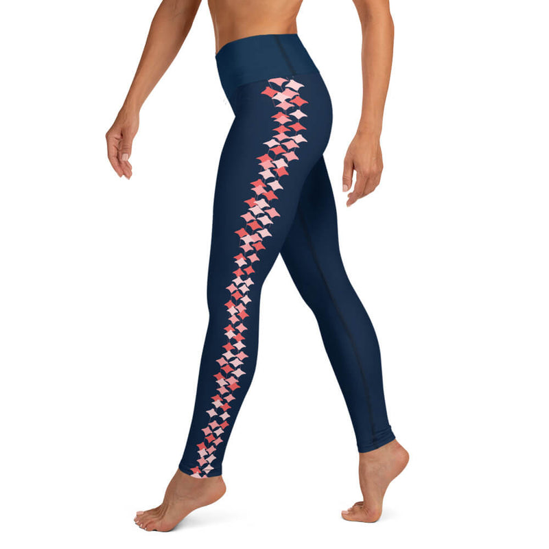 Left side view of a woman wearing navy blue leggings with a coral stingray pattern on the legs.