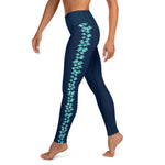 Left side view of woman wearing navy blue leggings with turquoise stingray pattern on the side of each leg.