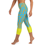 Left side view of model in Harlequin Filefish capri leggings, showing detail of turquoise, orange and yellow pattern.